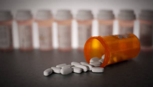 An orange bottle of pills on it's side with pills spilling out